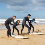 Group learning to surf on a sunny beach in Portugal. Perfect for lifestyle and travel themes.
